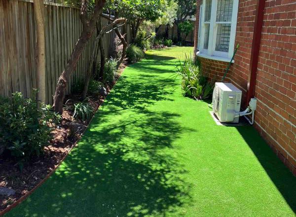 Synthetic turf latex against timber garden edge to crest a useful space for kids where grass struggled to grow.